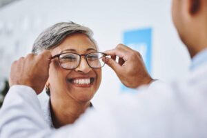 Adult wearing sunglasses outdoors while another person reviews an eye chart during a vision screening.